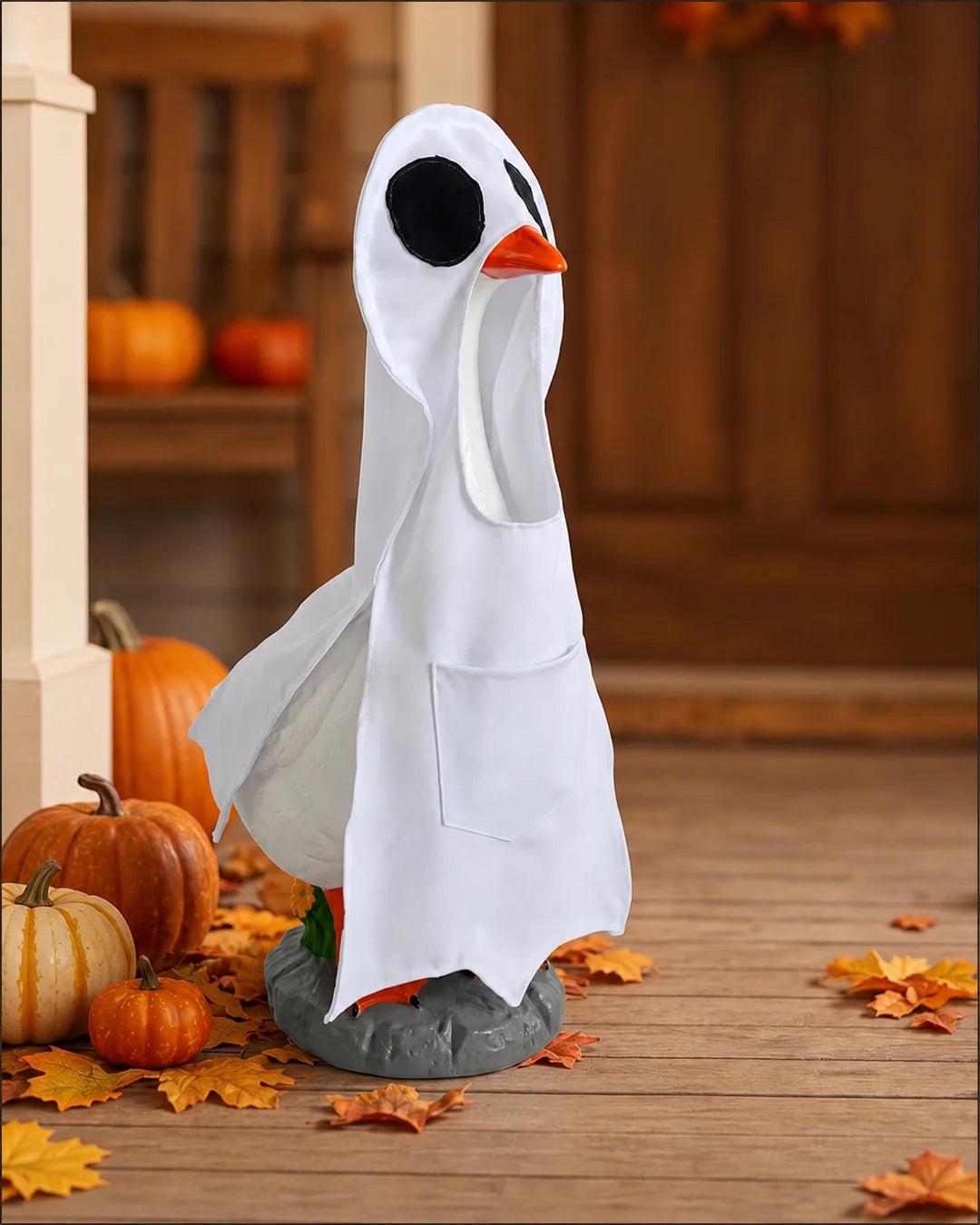 Porch goose wearing a crisp white ghost cloak beside fall pumpkins